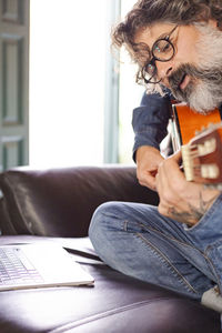 Bearded man learns to play acoustic guitar online