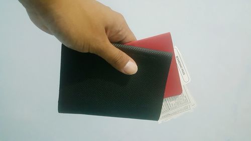 Close-up of hand holding book against white background