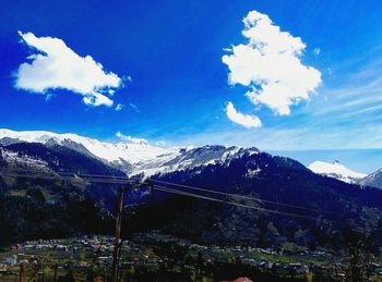 Scenic view of snow covered mountains against blue sky