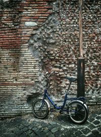 Bicycle parked against brick wall