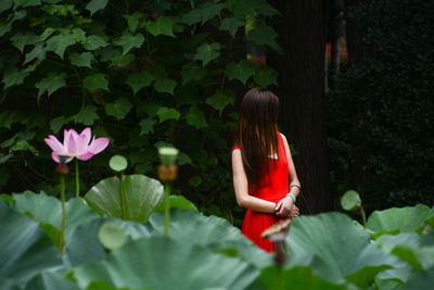 Woman wearing red dress standing in public park