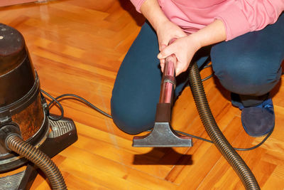 A middle-aged woman collects a vacuum cleaner for house cleaning.