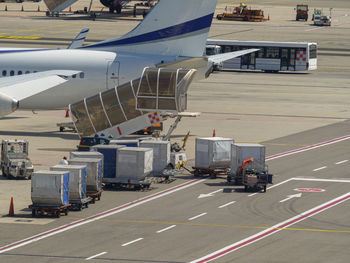 Metallic trolleys containing meals ready to be boarded on the flight line airplane near the runway.