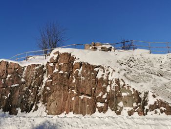 Low angle view of snow covered land against clear blue sky