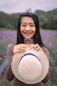 Portrait of young woman wearing hat while standing against lake