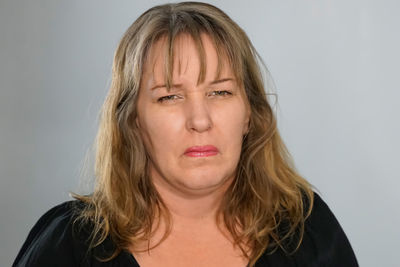 Portrait of woman making a face against gray background