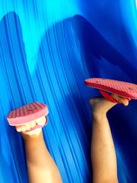 Low section of playful child wearing flip-flop sliding upside down on slide at playground