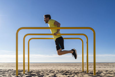 Athlete doing push ups on parallel bars at beach