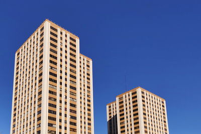 Low angle view of modern buildings against clear blue sky