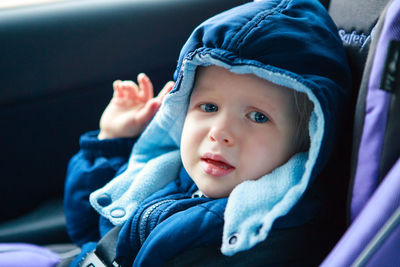 Crying sad caucasian baby infant sitting in car seat. kid in outwear clothes in automobile  carsit 