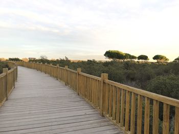 Footpath by railing against sky