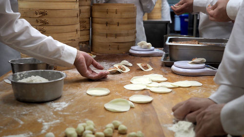 Midsection of preparing food on table at kitchen