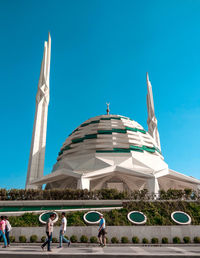 Mosque in city against clear blue sky