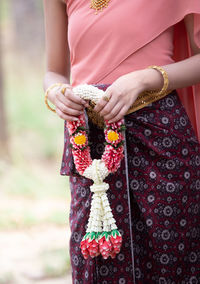 Midsection of bride holding floral garland while standing outdoors