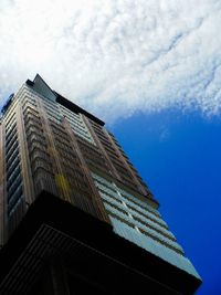 Low angle view of skyscrapers against cloudy sky