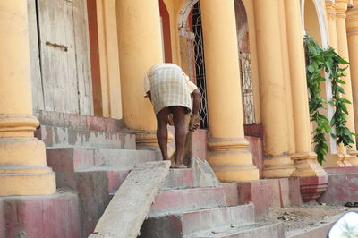 Rear view of woman standing on staircase by building