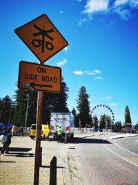 Road sign by street against blue sky
