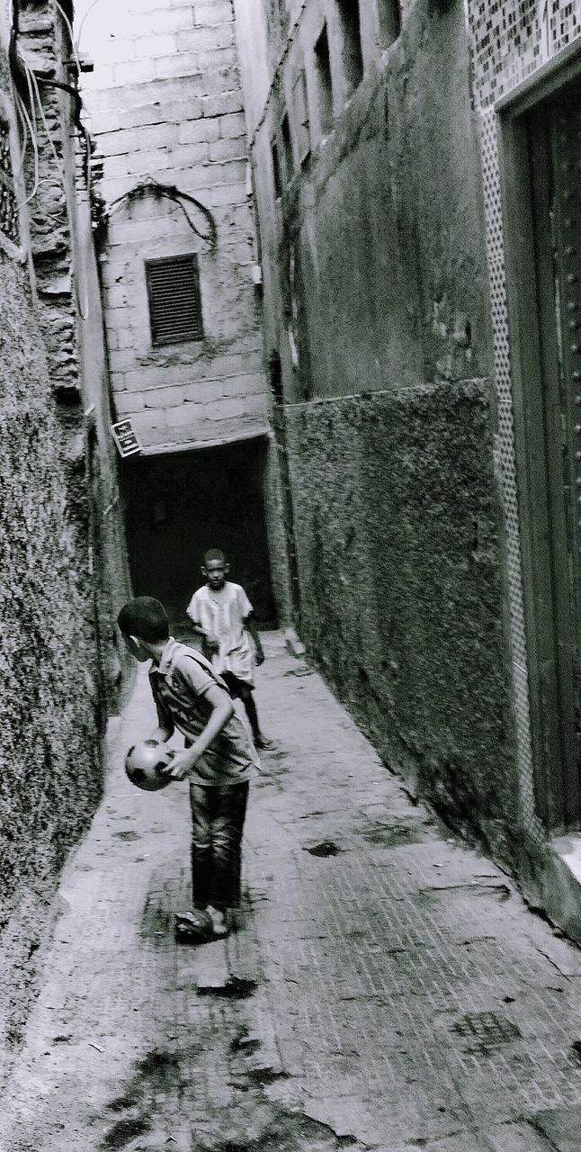 PEOPLE WALKING ON STREET AMIDST BUILDINGS IN CITY