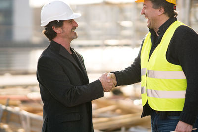 Happy architects shaking hands at construction site