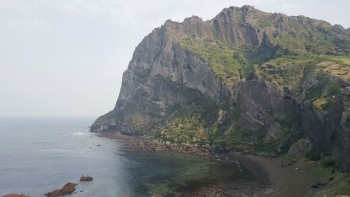 Scenic view of cliff by sea against clear sky