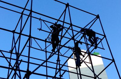 Low angle view of silhouette manual workers on scaffoldings against clear sky