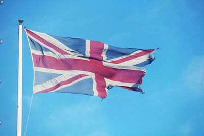 Low angle view of flag against blue sky