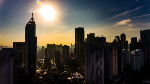 Modern buildings in city against sky during sunset