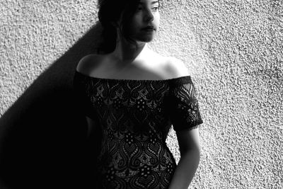 Young woman standing against wall