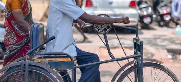 Midsection of man riding bicycle wheelchair