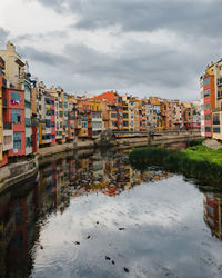 Buildings by river against sky in city