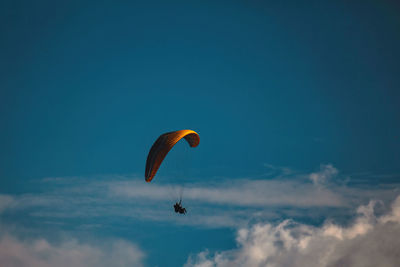 Low angle view of person paragliding against sky