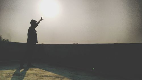 Silhouette boy standing against clear sky during sunset