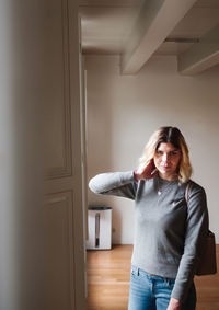 Portrait of woman standing against door at home