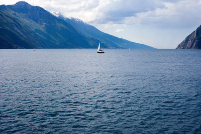 Sailboat in lake garda with mountains against sky