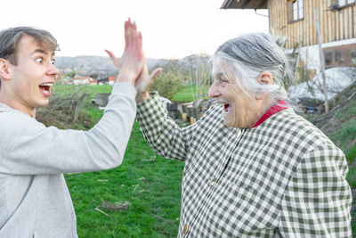 Happy grandmother giving high five with grandson on field