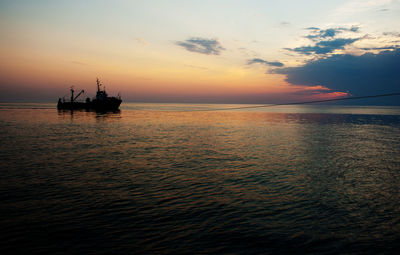 Silhouette boat in sea against sky during sunset