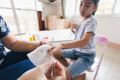 Parent helping her child perform first aid finger injury after she has been an accident.