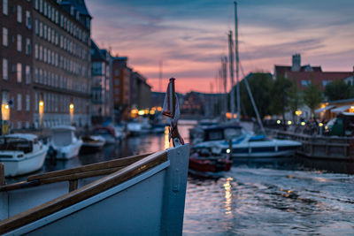 Sailboats moored on river in city at sunset