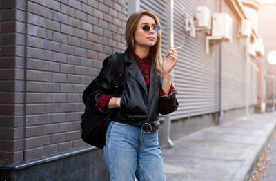 Full length of young woman standing against wall