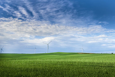 Wind turbines on field against sky