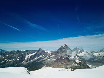 Scenic view of snowcapped mountains against blue sky