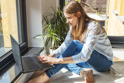 A girl sits on the floor in front of a laptop and makes purchases, chatting. work online. freelance