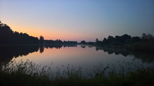 Scenic view of lake against clear sky during sunset