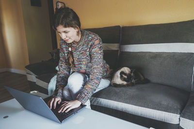 Woman using laptop while sitting on sofa