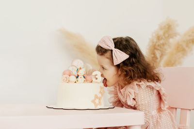 A charming little princess takes a bite out of a cake on her birthday