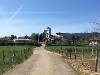 Road amidst buildings against sky