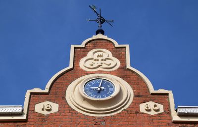 Low angle view of railroad station building against clear blue sky on sunny day