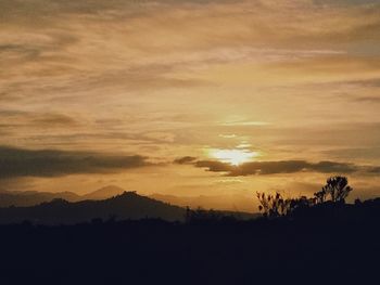 Silhouette landscape against dramatic sky during sunset