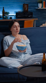 Woman looking away while sitting on table