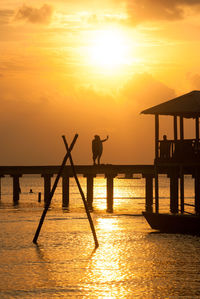 Pier in sea at sunset